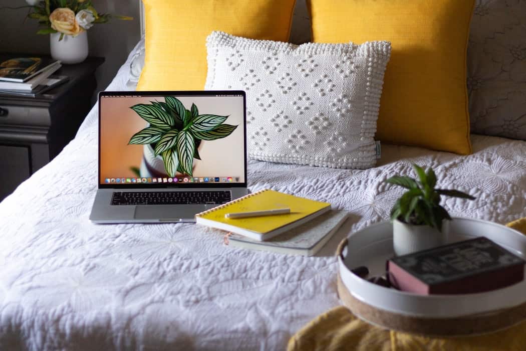 laptop and notebooks on a bed