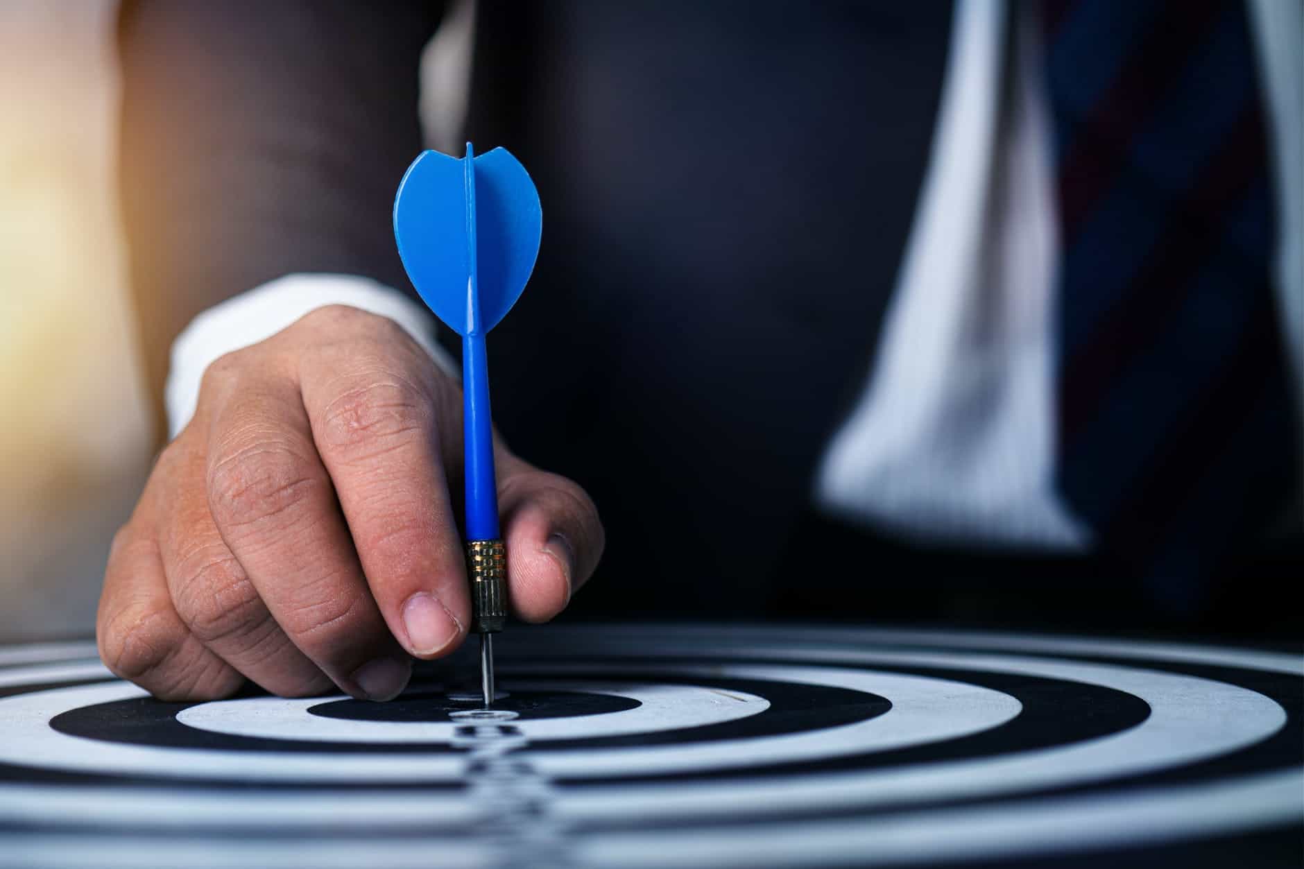 man pinning dart on dartboard