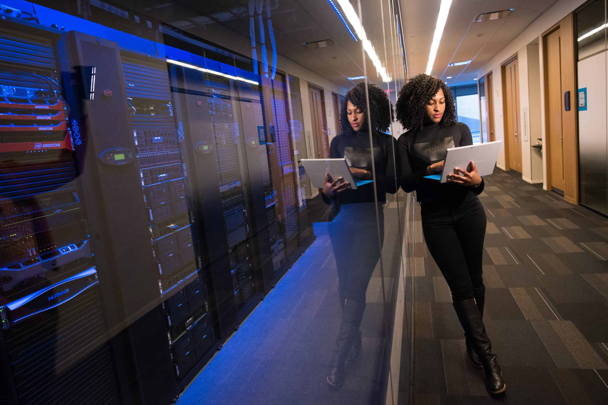 woman with laptop in front of mainframe computer