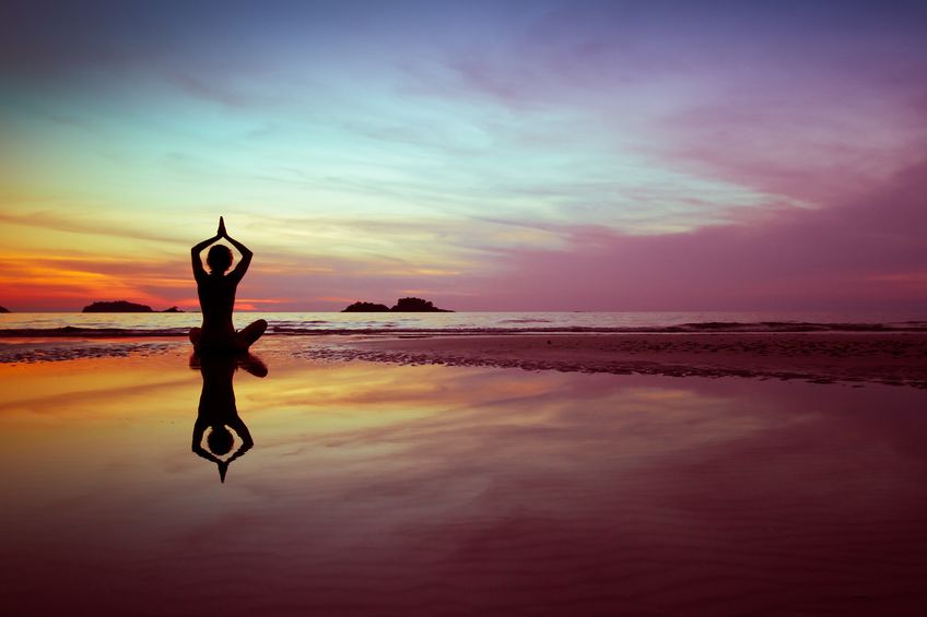 woman meditating near a calm body of water