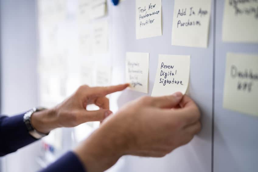 Close up shot of two businessmen pointing at a Kanban Board